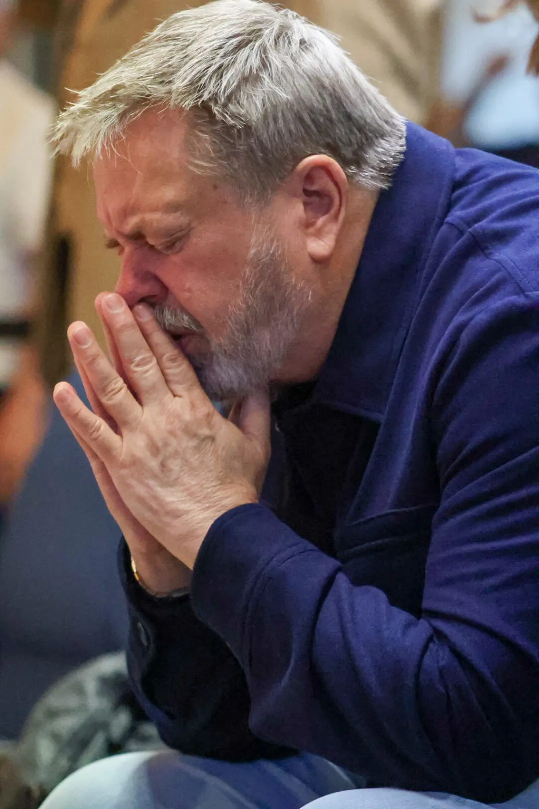 A man in prayer, hands pressed to his face